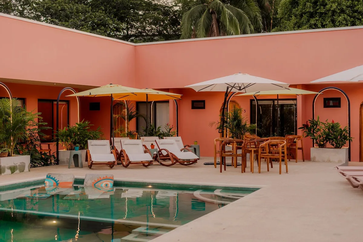 Pink courtyard with pool, umbrellas and loungers