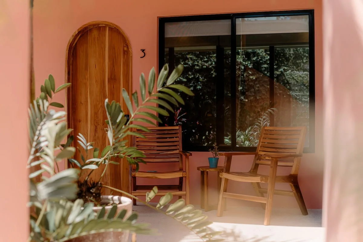 Arched wooden door and patio chairs outside a guest room